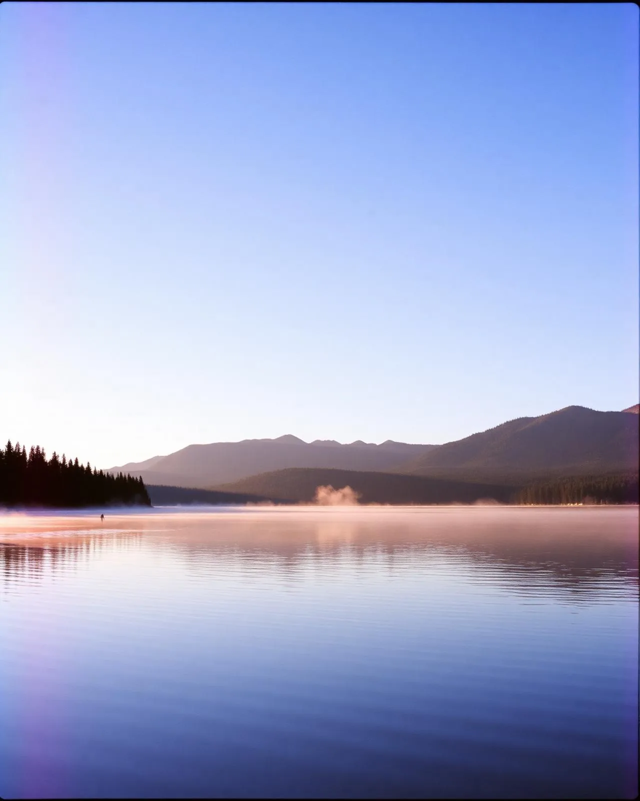 Mist rising off a still mountain lake at dawn